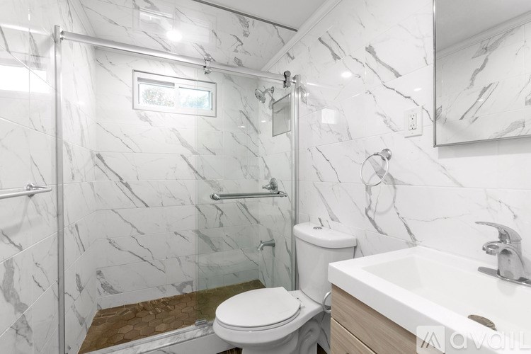 A bathroom with marble tiles on the walls and a white toilet.