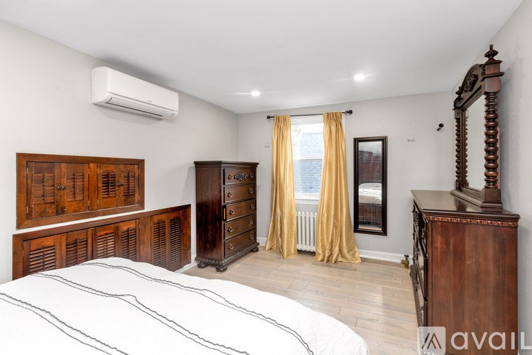 A bedroom with a large bed, wooden furniture, and a window with yellow curtains.