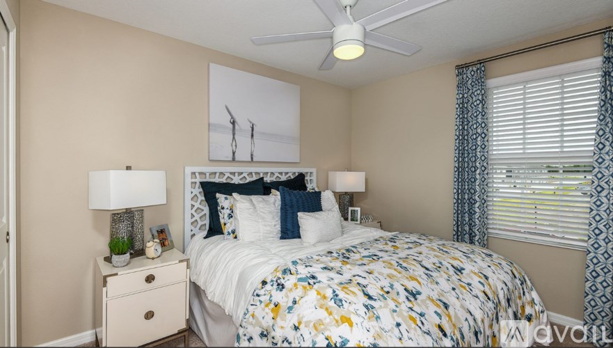 A bedroom with a bed, two lamps, and a ceiling fan.