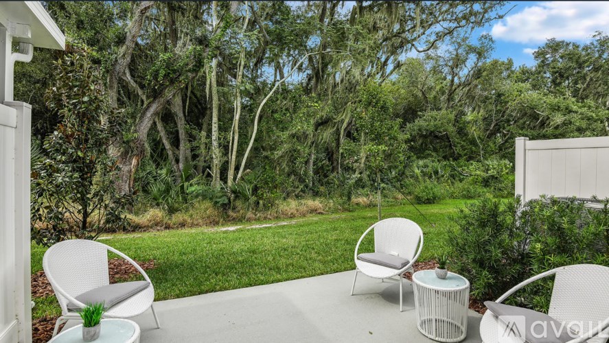 A white chair is on a patio with a table and a potted plant.