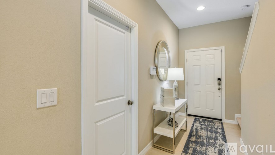 A hallway with a white door, a mirror, and a light switch.