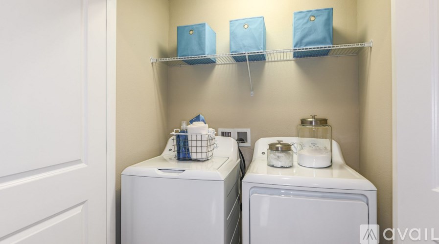 A laundry room with two washers and shelves above them.