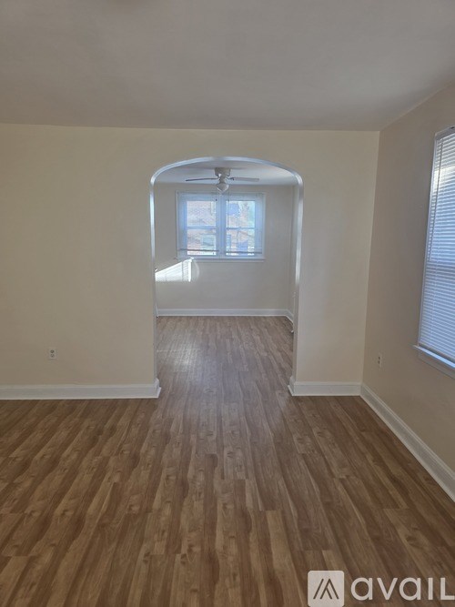 A room with wooden flooring and a window with blinds.