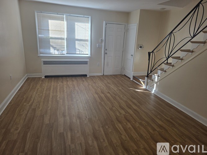 A room with wooden flooring and a staircase with metal railings.