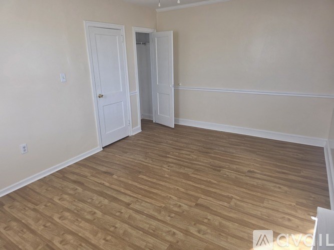A room with wooden flooring and two doors.