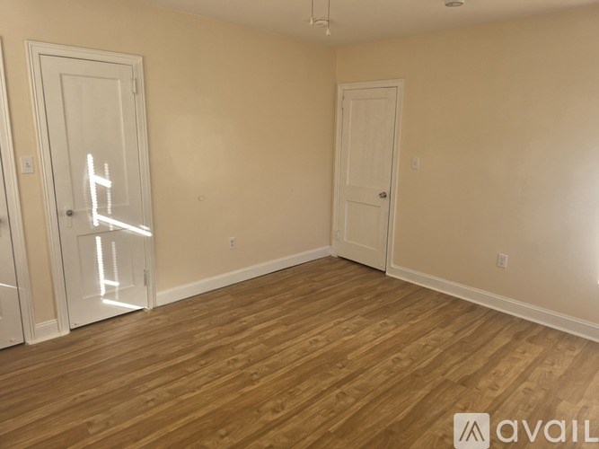 A room with wooden flooring and two white doors.