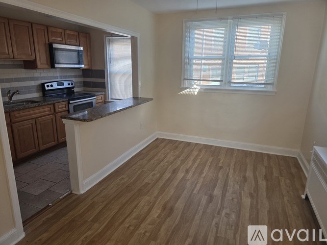 A kitchen with wooden floors and a window with blinds.