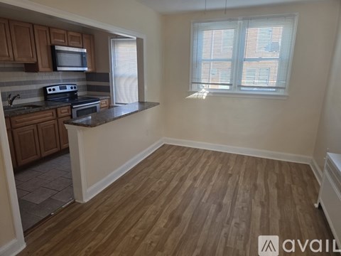 A kitchen with wooden floors and a window with blinds.