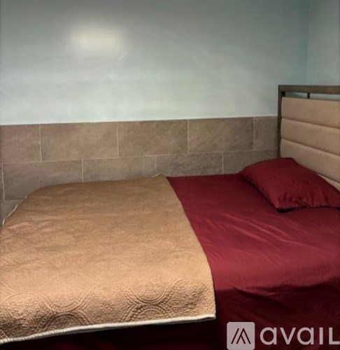 A bed with a tan and red comforter is in the image.