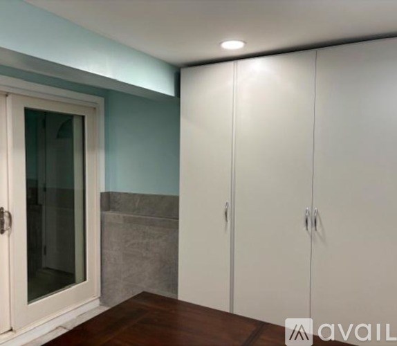 A white cabinet with a glass door is in a room with a blue wall.