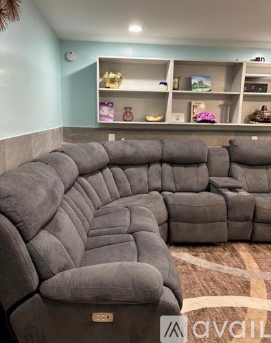 A row of grey sofas in a room with a shelf in the background.