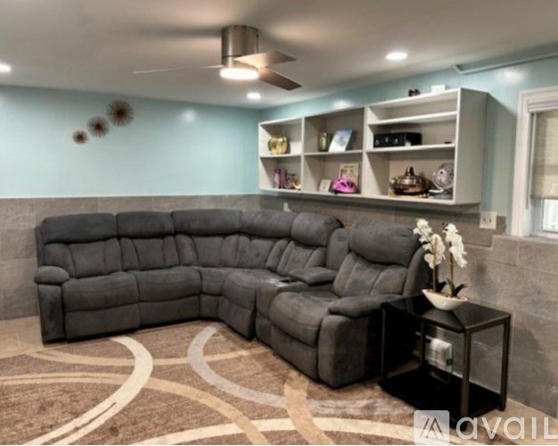 A black sectional sofa with a glass table in front of it.
