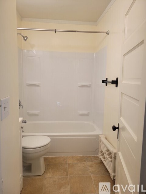 A white bathroom with a toilet, tub, and shower.