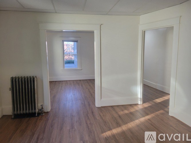 A room with a window, a radiator, and wooden flooring.