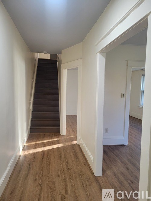 A hallway with wooden floors and a staircase.