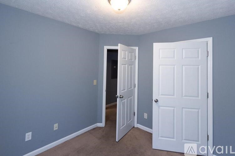 A room with two doors, one open, and a light on the ceiling.