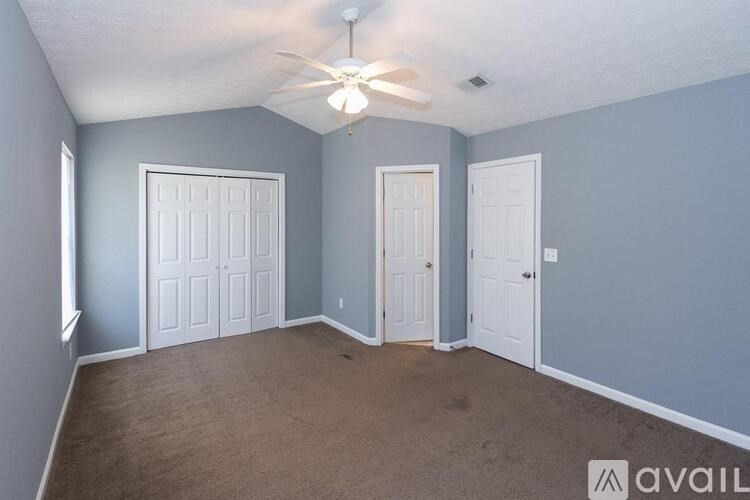A room with a ceiling fan and three doors.