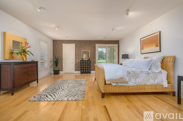 A bedroom with a zebra rug on the floor and a couch with a white comforter on it.