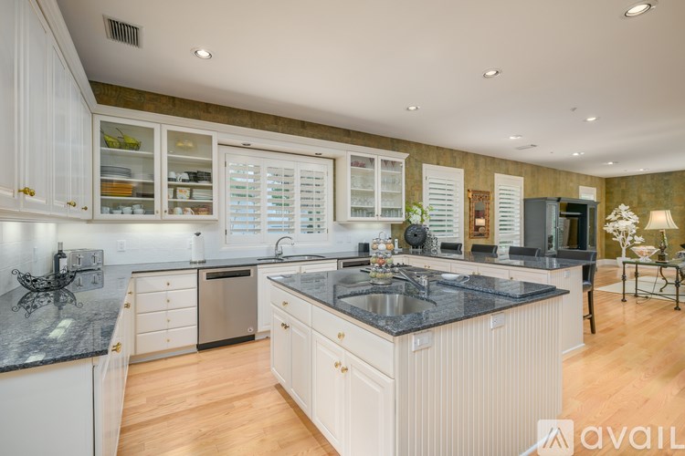 A kitchen with white cabinets and a black countertop.
