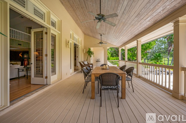 A wooden deck with a table and chairs and a ceiling fan.