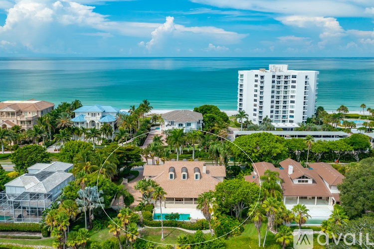 A bird's eye view of a resort with a large swimming pool and a tall white hotel building.