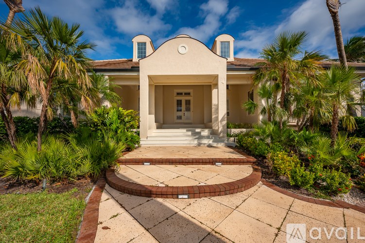 A house with a front yard and palm trees.