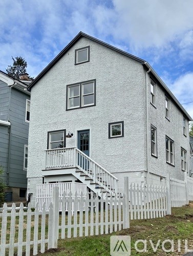 A white house with a black roof and a white picket fence.