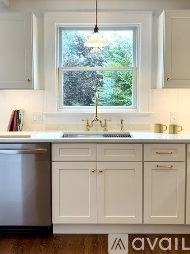 A kitchen with white cabinets and a window.