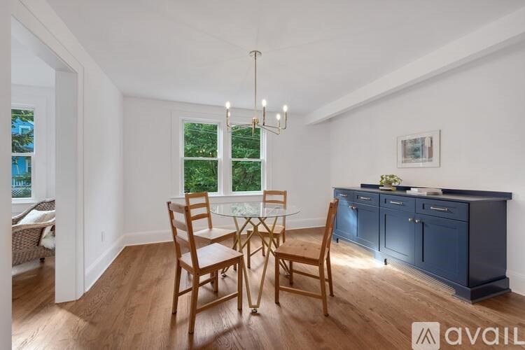 A dining room with a table set for two and a chandelier hanging from the ceiling.