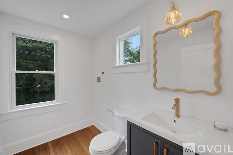 A bathroom with a toilet, sink, and mirror.