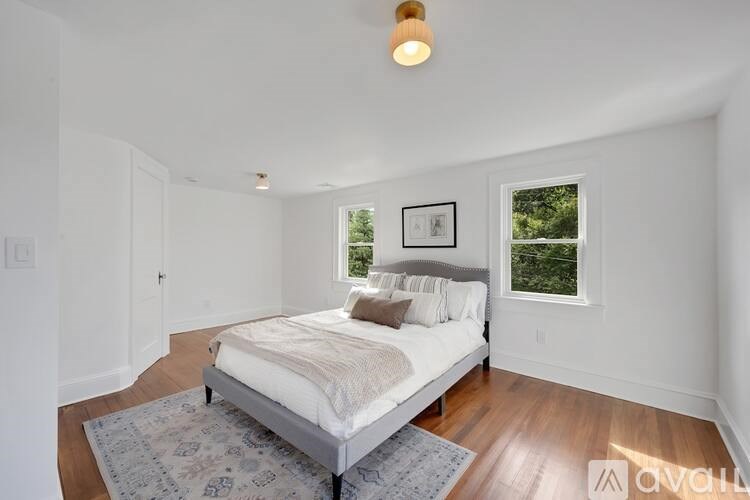 A bedroom with a bed, a rug, and a picture on the wall.