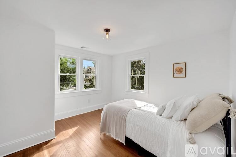 A bedroom with a bed and a window overlooking a house.