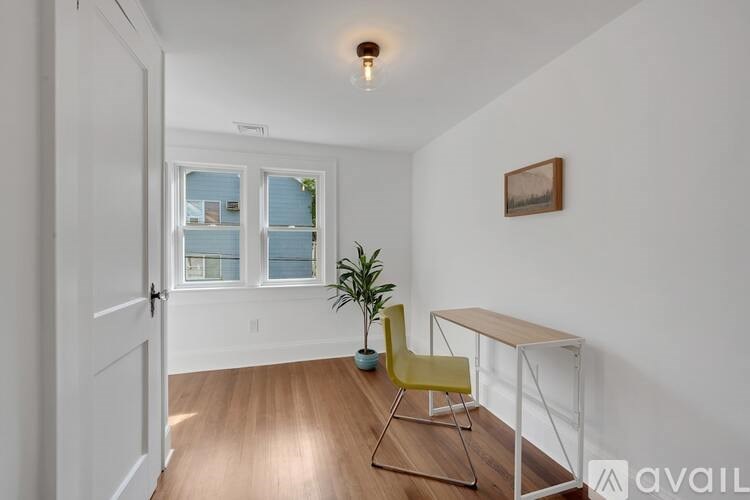 A room with a yellow chair and a small table with a plant on it.