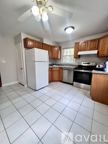 A kitchen with white tile flooring and wooden cabinets.