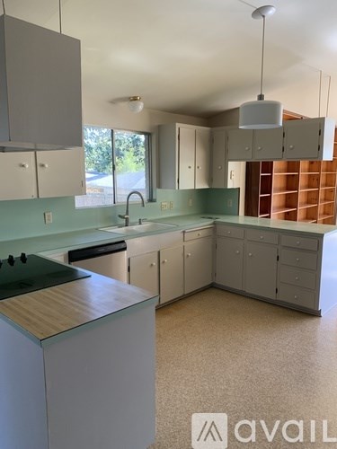 A kitchen with a green counter top and white cabinets.