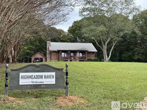A sign that says Highmeadow Haven stands in front of a house.