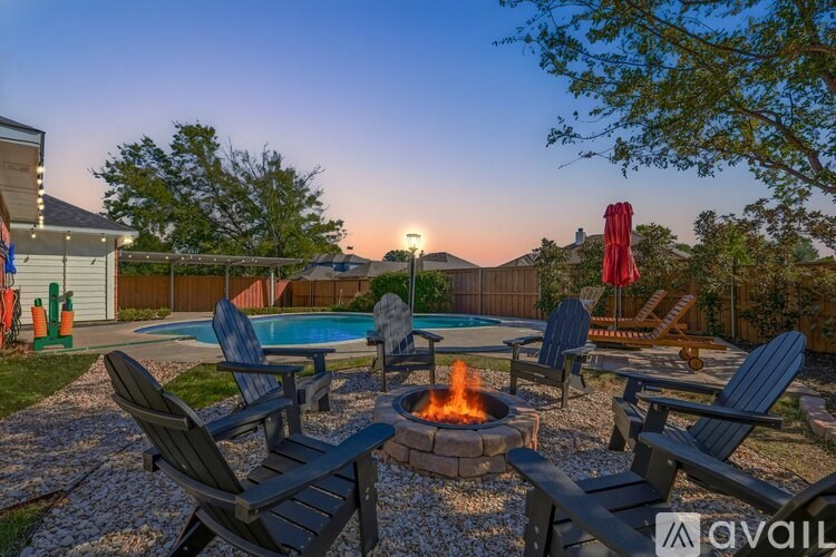 A backyard with a fire pit and chairs.