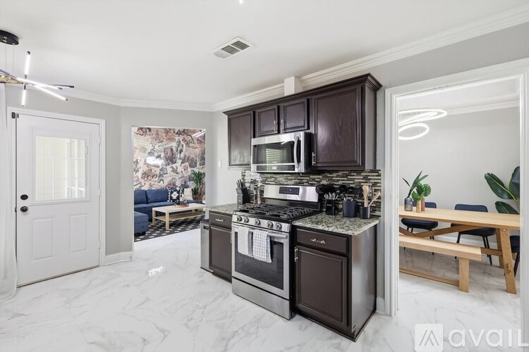 A kitchen with a stove top oven and microwave built into a dark brown cabinet.