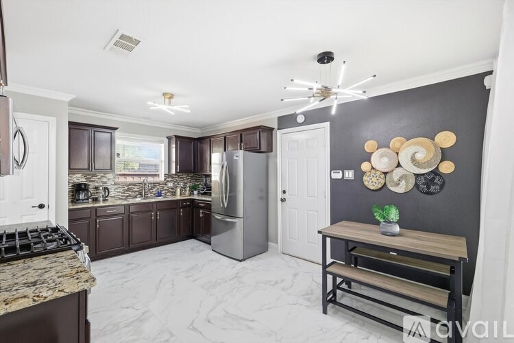 A kitchen with a marble countertop and a stainless steel refrigerator.