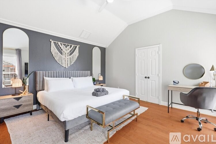 A bedroom with a bed, a chair, and a mirror.