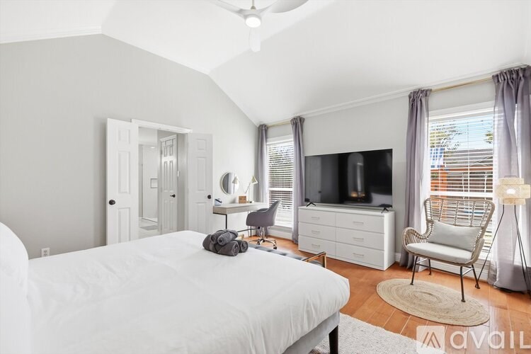 A bedroom with a bed, chair, and television.
