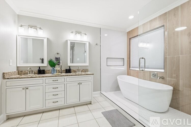 A modern bathroom with a white tub and double sinks.