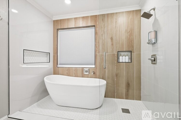 A modern bathroom with a white bathtub and wooden wall paneling.