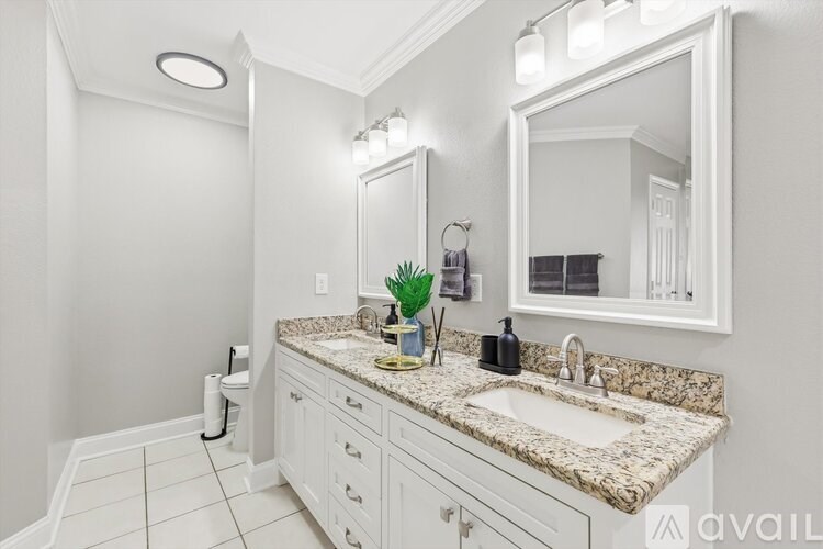 A bathroom with a granite countertop and a large mirror.