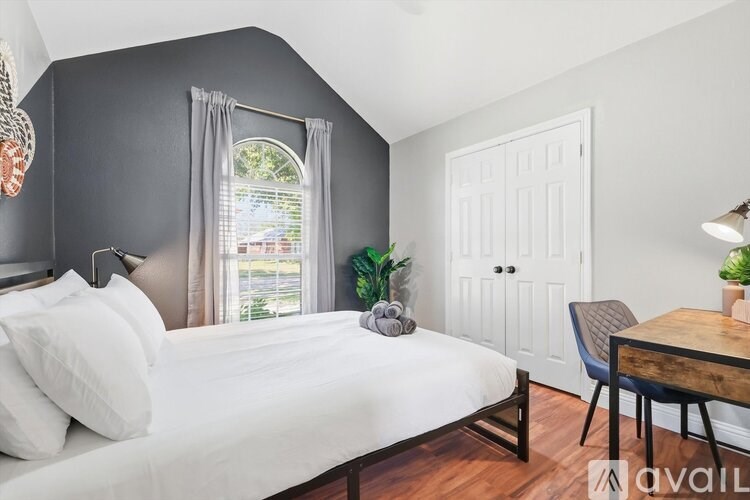 A bedroom with a bed, a chair, and a window.