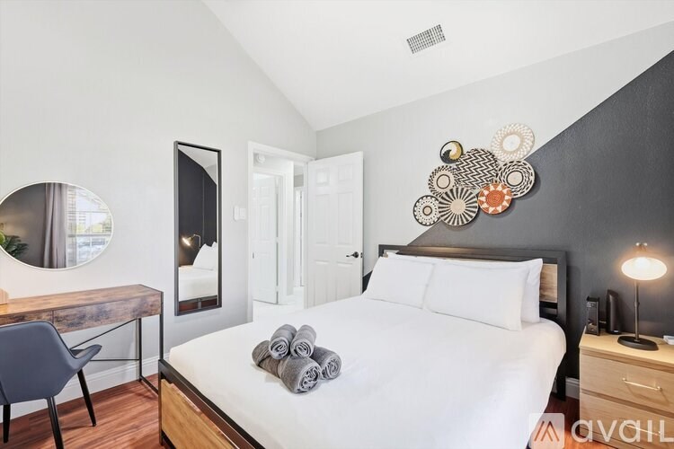 A bedroom with a large bed, a desk with a chair, and a mirror on the wall.