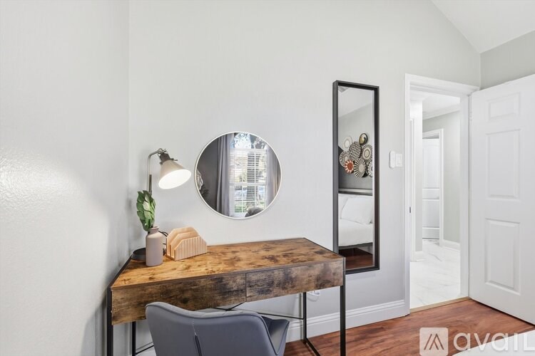 A wooden table with a round mirror above it and a chair in front of it.