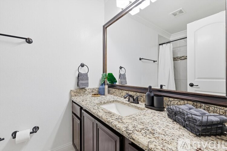 A bathroom with a marble countertop and a large mirror.