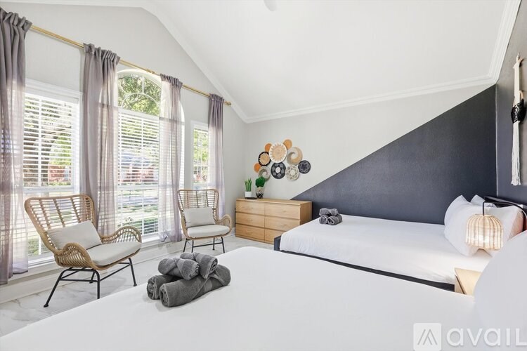 A bedroom with a large bed, two chairs, and a dresser with a mirror.