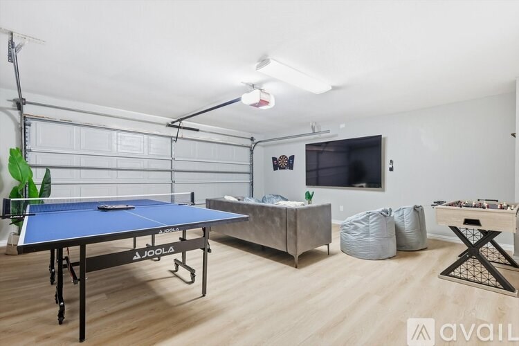 A JOOLA table tennis table is in a room with a TV, bean bag chairs, and a wooden floor.